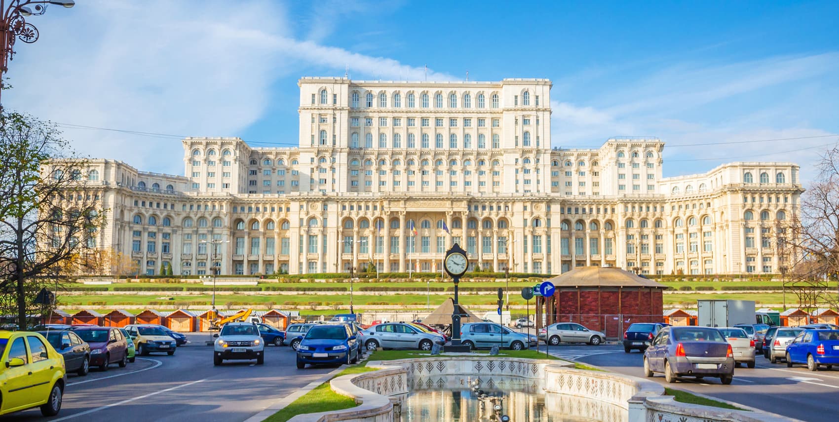The Palace of the Parliament in Bucharest, Romania – an iconic landmark and popular conference venue, captured on a sunny day with cars and a fountain in the foreground.